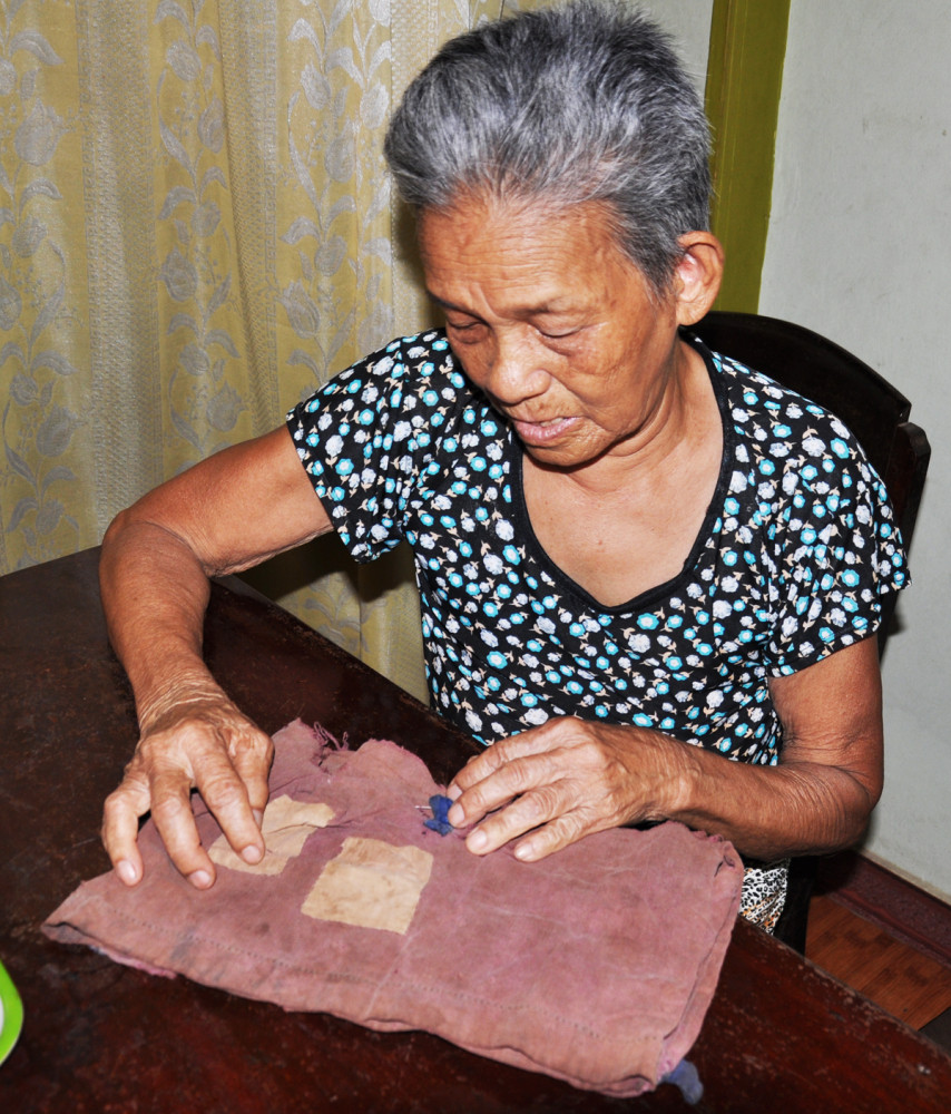 Mẹ Nguyễn Thị Em và chiếc túi vải còn lại được gìn giữ hơn nửa thế kỷ của đứa con trai bé bỏng chết vì bom Mỹ trên đường sơ tán của chiến dịch K8 khi mới 7 tuổi - Ảnh: L.Đ.D
