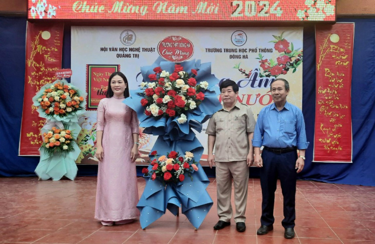 Cô giáo Tạ Thị Thu Hiền - Hiệu trưởng Trường THPT Đông Hà tặng hoa chúc mừng nhân Ngày Thơ Việt Nam - Ảnh: L.T